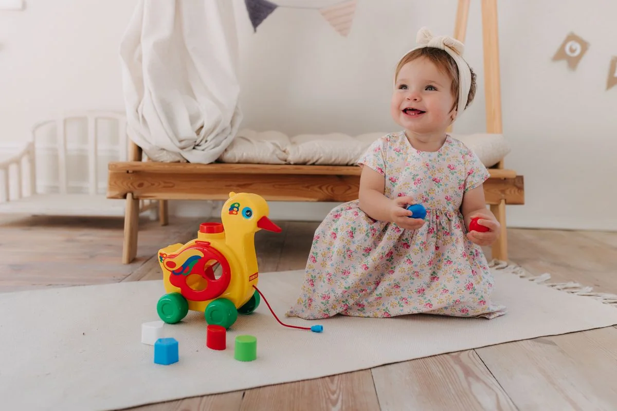 A smiling infant playing with a colorful developmental toy